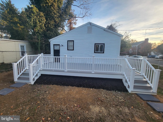 back house at dusk featuring a deck