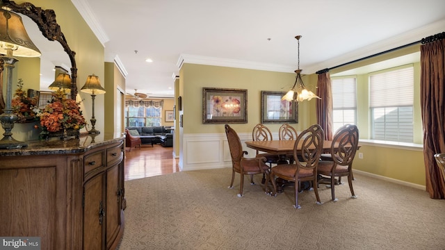 carpeted dining room featuring a healthy amount of sunlight, ornamental molding, and ceiling fan with notable chandelier