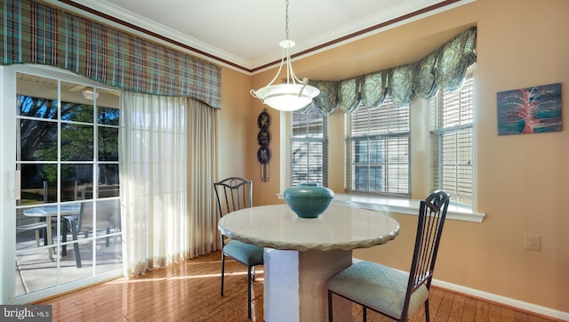 dining area featuring wood-type flooring and crown molding