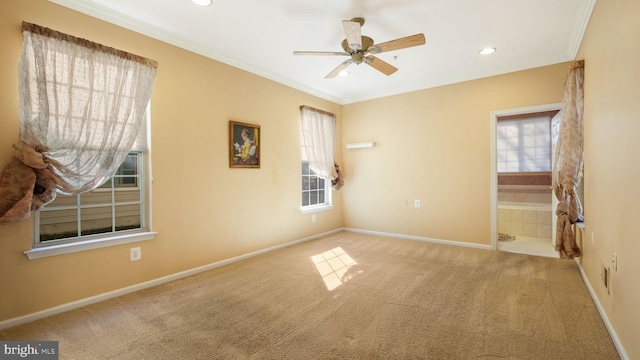 carpeted spare room with ceiling fan, crown molding, and plenty of natural light