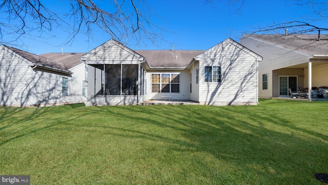 rear view of property featuring a lawn, a sunroom, and a patio area