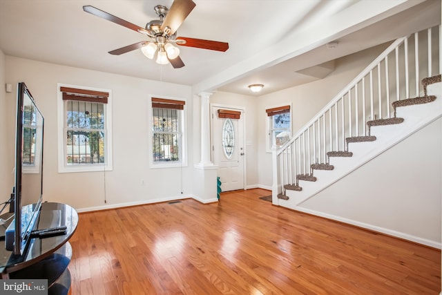 entryway with ceiling fan, wood-type flooring, and decorative columns