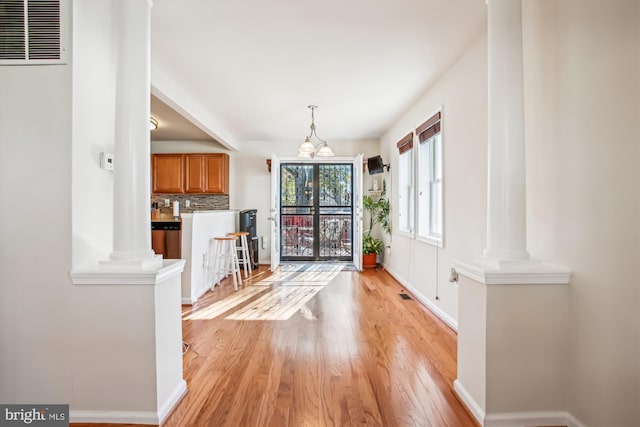 interior space featuring decorative columns, light hardwood / wood-style flooring, and a chandelier