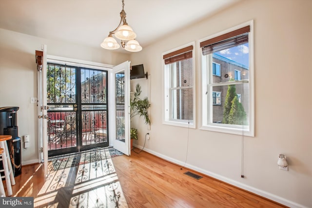 doorway to outside featuring a chandelier and light wood-type flooring