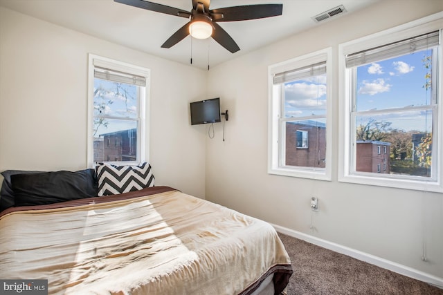 carpeted bedroom with multiple windows and ceiling fan