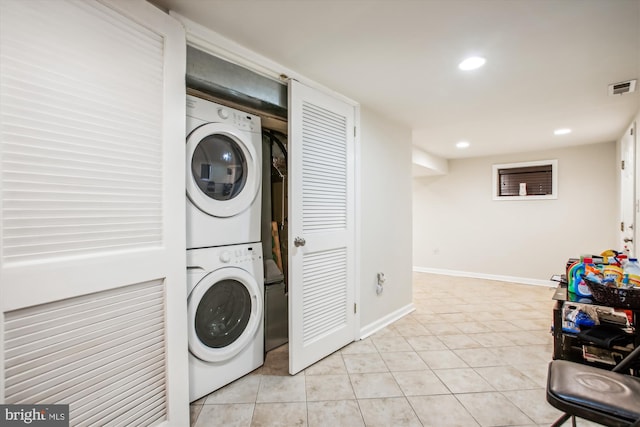 washroom with light tile patterned floors and stacked washer and dryer