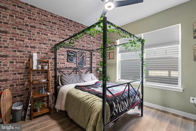 bedroom featuring hardwood / wood-style floors, ceiling fan, and brick wall