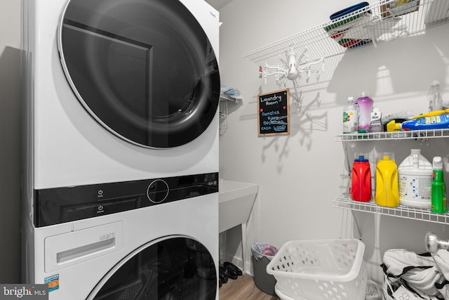 laundry area featuring hardwood / wood-style floors and stacked washer / drying machine