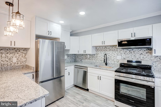 kitchen with appliances with stainless steel finishes, crown molding, sink, white cabinetry, and hanging light fixtures