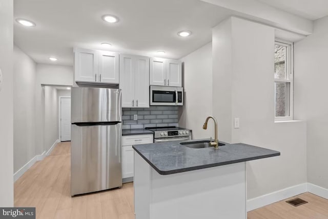 kitchen featuring appliances with stainless steel finishes, light wood-type flooring, white cabinetry, and sink