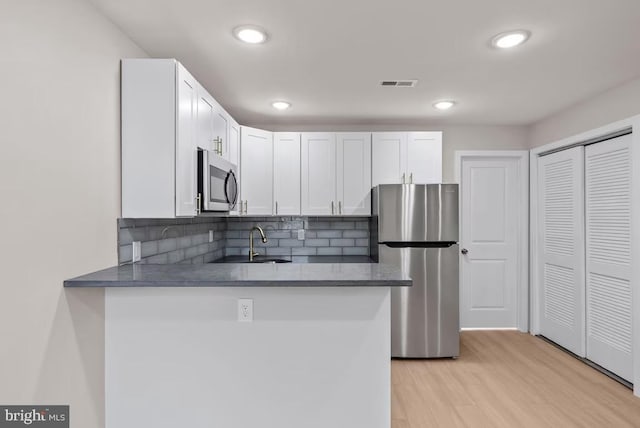 910 N Markoe St, Philadelphia, PA 19131 - kitchen featuring appliances with stainless steel finishes, a sink, decorative backsplash, a peninsula, and white cabinets