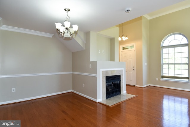 unfurnished living room featuring hardwood / wood-style floors, a notable chandelier, and ornamental molding