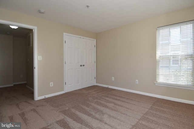 unfurnished bedroom with carpet flooring, a closet, and multiple windows