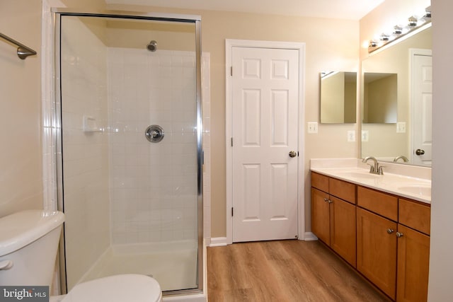 bathroom with hardwood / wood-style floors, vanity, toilet, and a shower with shower door