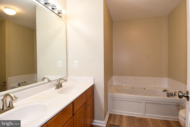 bathroom with a bath, hardwood / wood-style floors, vanity, and toilet