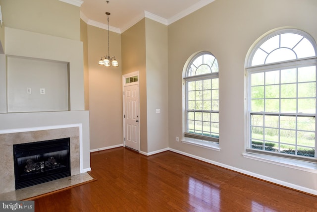 unfurnished living room featuring a healthy amount of sunlight, a premium fireplace, dark wood-type flooring, and an inviting chandelier