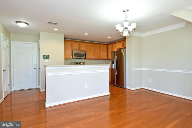 kitchen featuring ornamental molding, light hardwood / wood-style flooring, hanging light fixtures, and appliances with stainless steel finishes