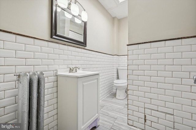 bathroom with vanity, tile walls, and toilet