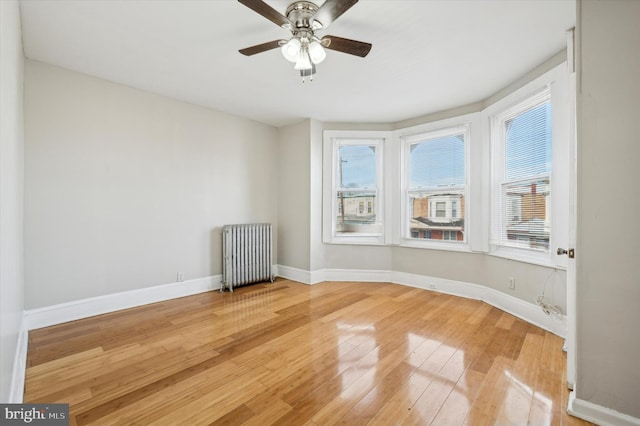 spare room featuring wood-type flooring, radiator, and ceiling fan