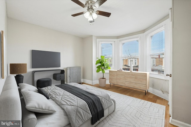 bedroom featuring radiator heating unit, light hardwood / wood-style flooring, and ceiling fan