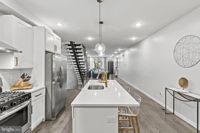 kitchen with hardwood / wood-style floors, a kitchen island with sink, sink, white cabinetry, and stainless steel appliances