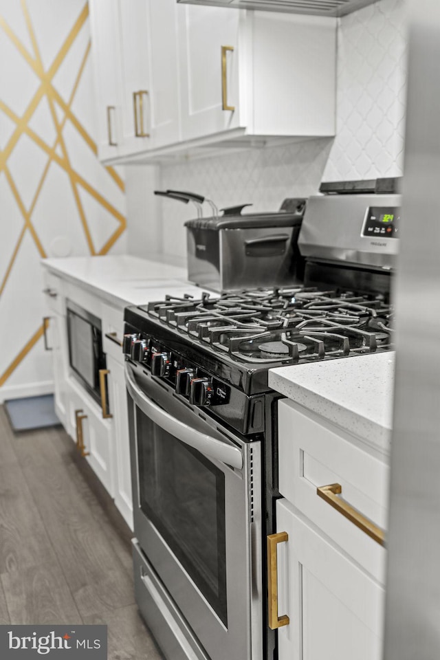 kitchen with backsplash, gas range, dark hardwood / wood-style flooring, light stone counters, and white cabinetry