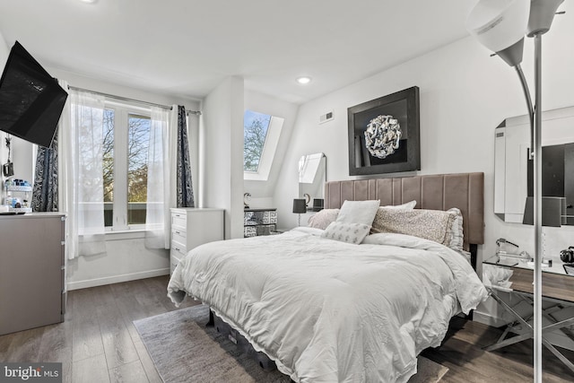 bedroom with dark hardwood / wood-style floors and a skylight