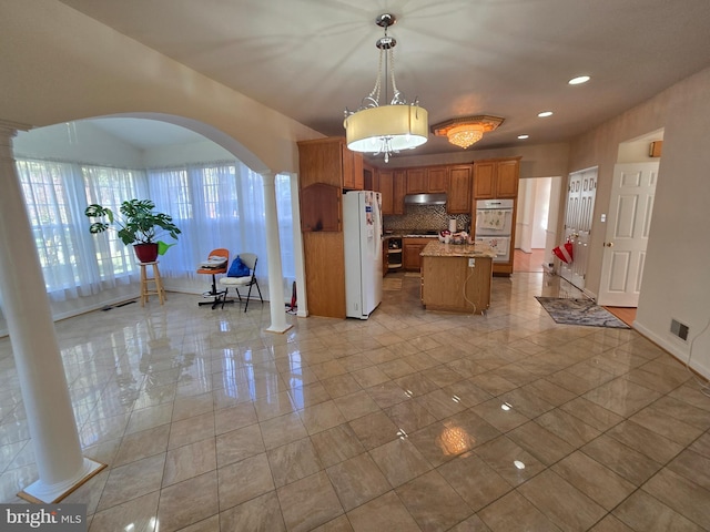 kitchen featuring a center island, white appliances, tasteful backsplash, decorative light fixtures, and decorative columns