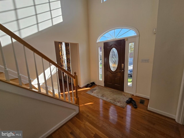 entryway featuring a towering ceiling and hardwood / wood-style flooring