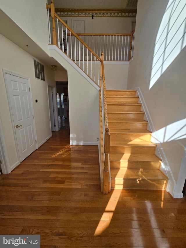 stairway featuring wood-type flooring and a high ceiling