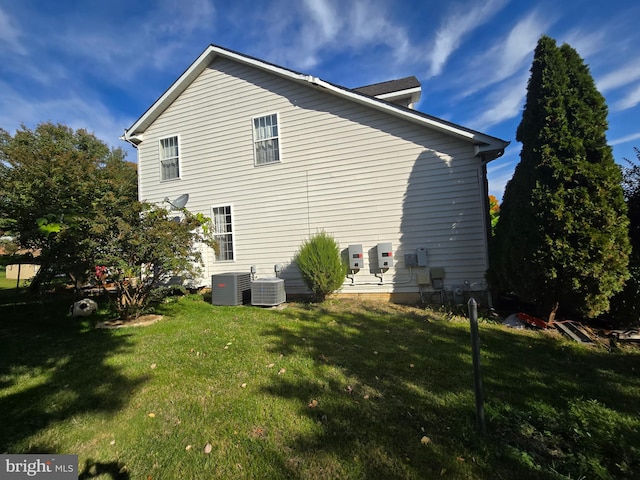 view of side of home with central air condition unit and a yard