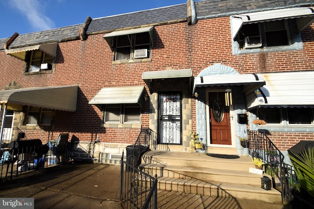 view of property with a shingled roof, brick siding, and mansard roof