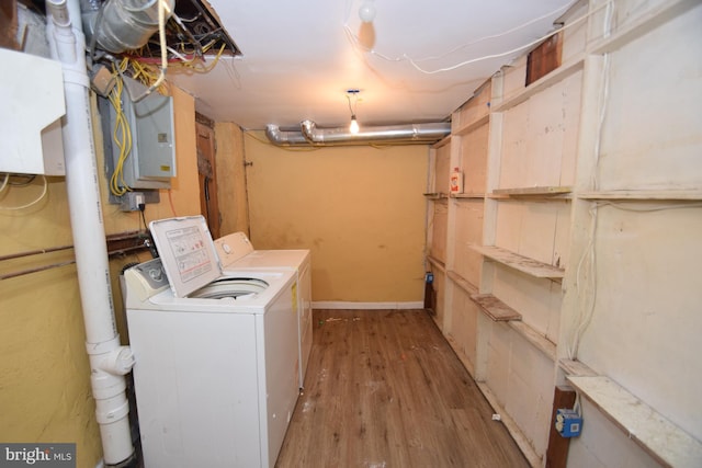 washroom featuring laundry area, washing machine and dryer, electric panel, and wood finished floors