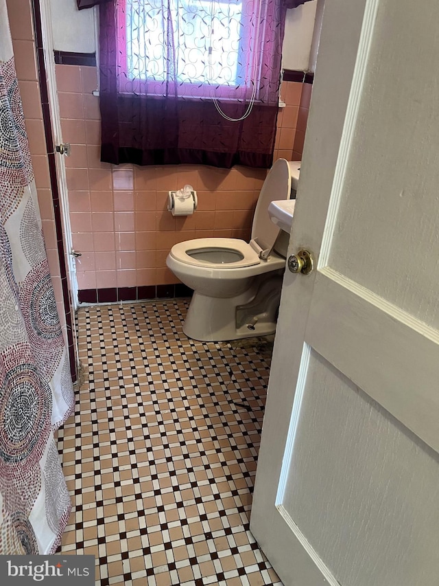 bathroom featuring tile walls and toilet