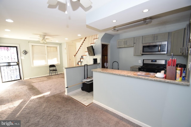 kitchen with a ceiling fan, light colored carpet, stainless steel appliances, light countertops, and gray cabinetry