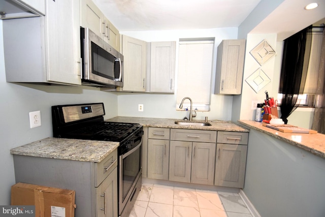 kitchen featuring marble finish floor, stainless steel appliances, a sink, and light stone countertops