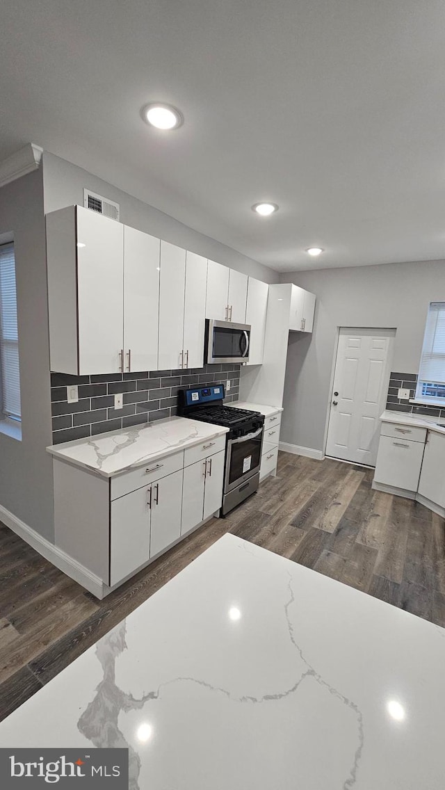 kitchen featuring white cabinetry, light stone countertops, dark hardwood / wood-style floors, and stainless steel appliances