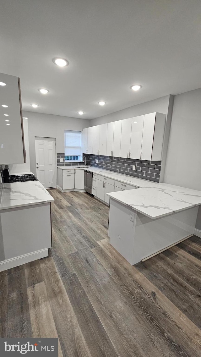 kitchen featuring white cabinetry, kitchen peninsula, light stone countertops, dark hardwood / wood-style floors, and dishwasher