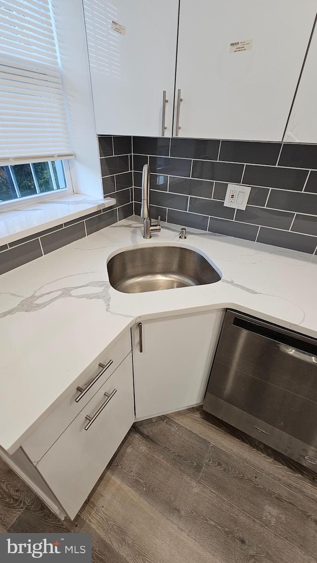 kitchen with white cabinetry, hardwood / wood-style floors, sink, and light stone counters