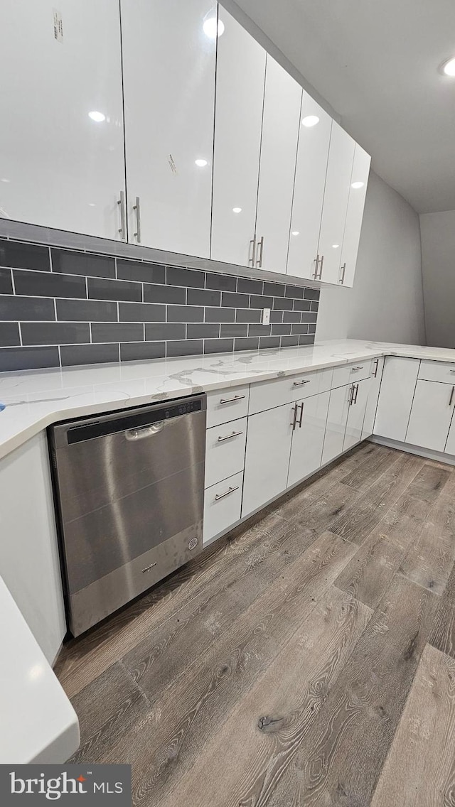 kitchen with white cabinetry, light stone countertops, decorative backsplash, dark wood-type flooring, and stainless steel dishwasher