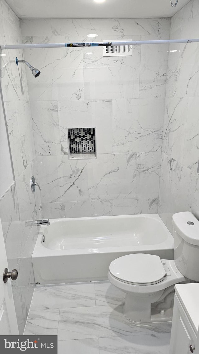 full bathroom featuring tile walls, vanity, tiled shower / bath combo, and toilet