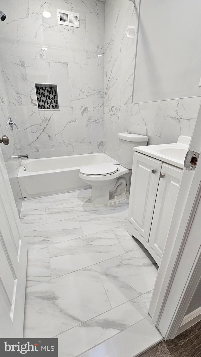 full bathroom with toilet, tiled shower / bath combo, vanity, and tile walls