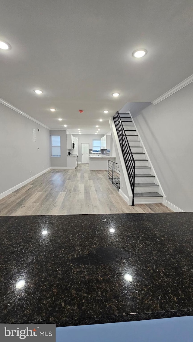 basement with ornamental molding, a wealth of natural light, and light hardwood / wood-style floors