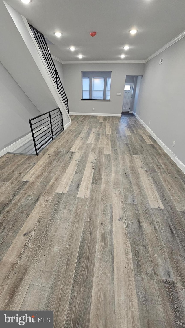 unfurnished living room with hardwood / wood-style floors and crown molding