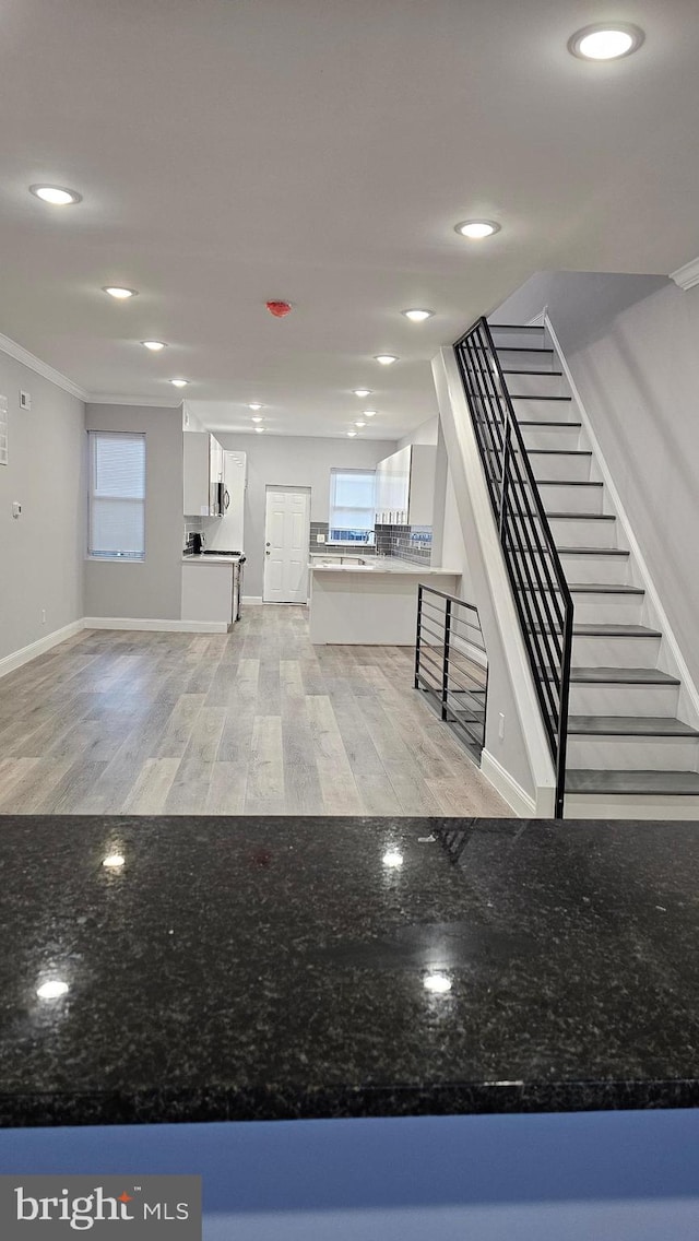 interior space featuring white cabinetry, light hardwood / wood-style flooring, and crown molding