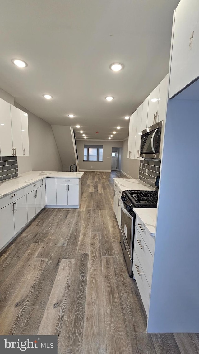 kitchen with white cabinetry, kitchen peninsula, appliances with stainless steel finishes, and dark wood-type flooring