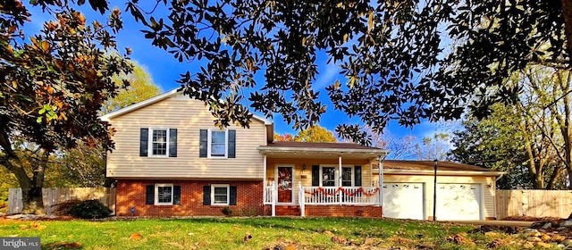 tri-level home with a porch, a garage, and a front lawn