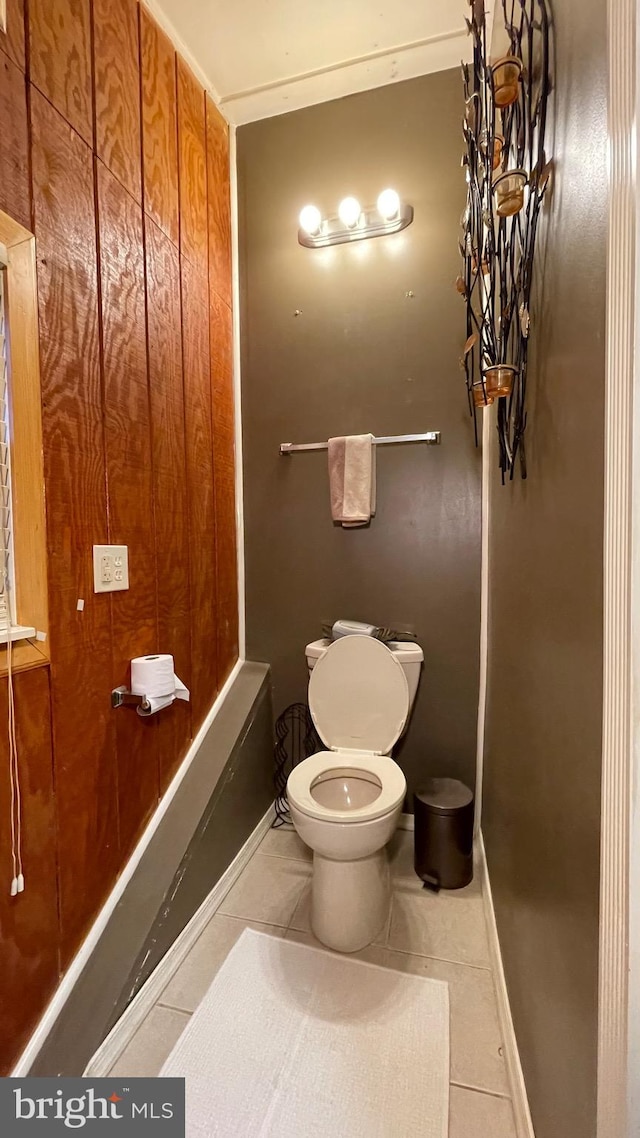 bathroom with wooden walls, toilet, and tile patterned floors