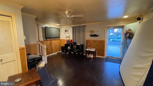 interior space with hardwood / wood-style floors, wooden walls, ceiling fan, and crown molding