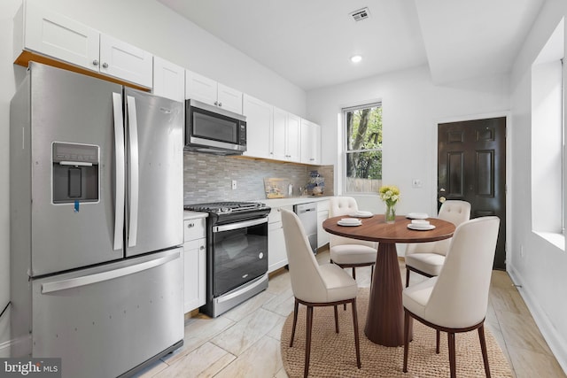 kitchen featuring decorative backsplash, appliances with stainless steel finishes, and white cabinetry